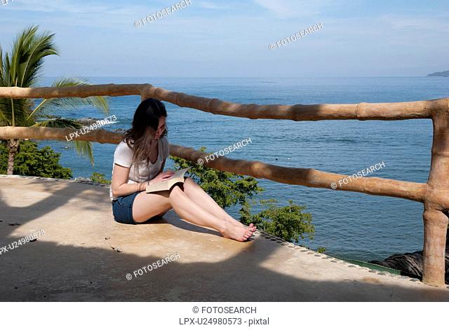 Teenage girl reading a book at the seaside, Sayulita, Nayarit, Mexico