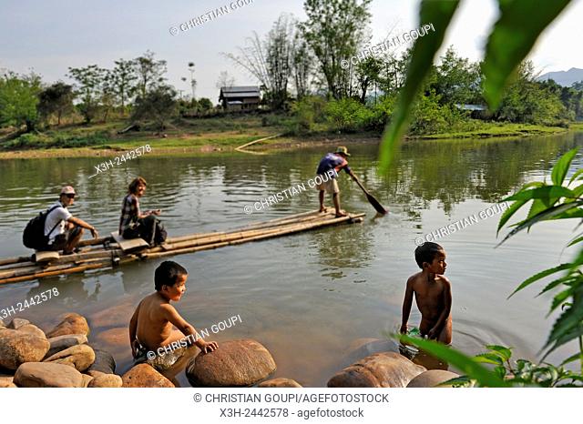 two children playing at the water'edge, bamboo raft for crossing the Nam Pak River, Muang La, Oudomxay Province in northwestern Laos, Southeast Asia