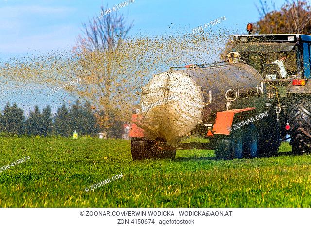Ein Traktor düngt mit Gülle ein Feld im Herbst