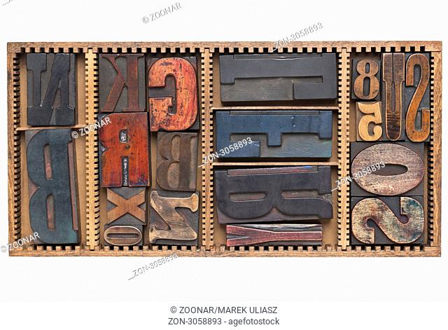 letters and numbers - a variety of vintage letterpress printing blocks in a small wooden typesetter box with dividers, isolated on white