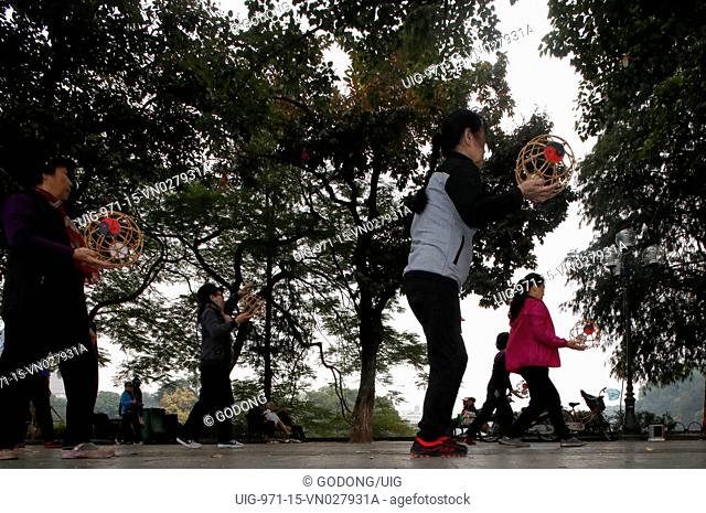 Early morning tai chi session along the banks of Hoan Kiem lake. Exercises with fans. Hanoi, Vietnam