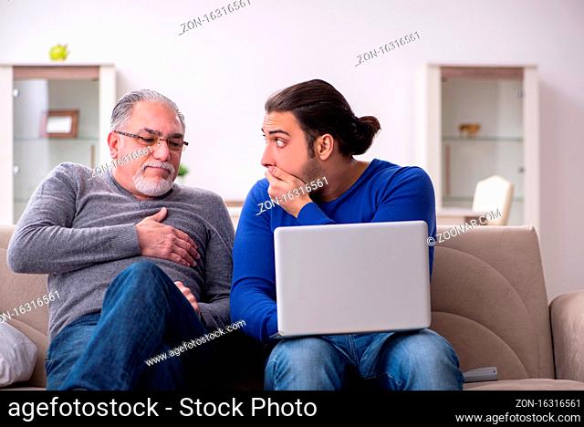 Father and son sitting on the sofa with the computer