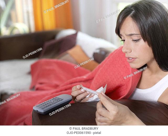Woman in living room taking her own temperature