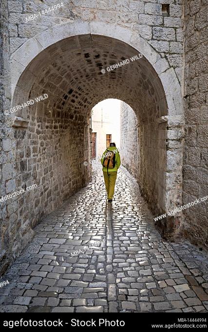 A woman walks through a passageway, Old Town Trogir, UNESCO World Heritage Site, Split-Dalmatia County, Dalmatia, Croatia, Europe