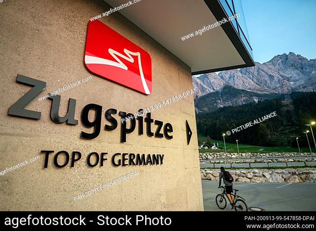 13 September 2020, Bavaria, Eibsee: After sunset, a cyclist cycles along the sign for the Zugspitze. Photo: Lino Mirgeler/dpa