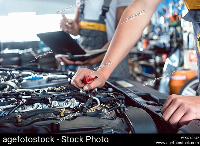 Close-up of a screwdriver held by a skilled mechanic before repairing the engine, after scanning the errors with a diagnostic software in a modern automobile...