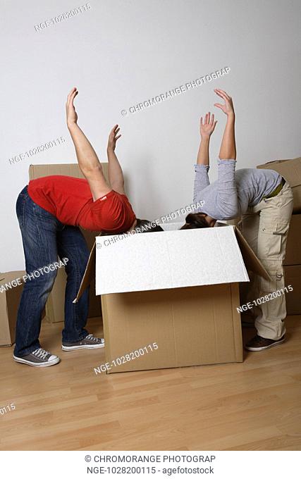 Young Couple sticking there heads in box, arms aloft