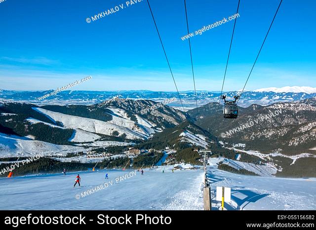 Low Tatras. Slovak ski resort Jasna in sunny weather. Ski slope and lift cabin. Blue sky over the mountain peaks