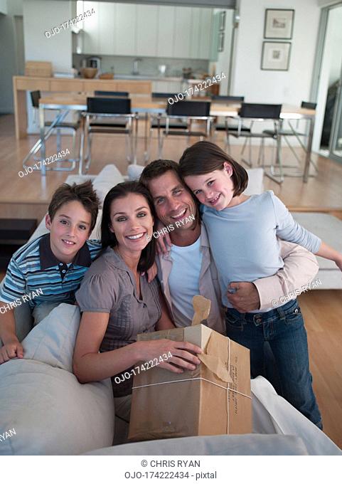 Man and woman with boy and girl sitting on sofa with package