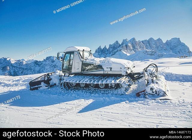 Italy, Veneto, Belluno, Falcade, a snowcat in the skislopes near Laresei refuge, Pale di San Martino group in the background, San Pellegrino ski area, Dolomites