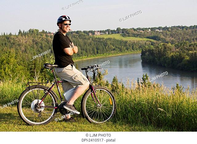 Man riding his electric bicycle with Edmonton city skyline in the background; Edmonton, Alberta, Canada