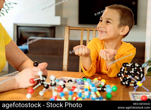 Smiling boy looking at mother by helix model on table