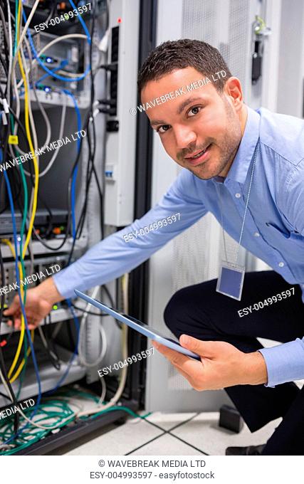 Technician plugging in cables and using tablet pc in data center