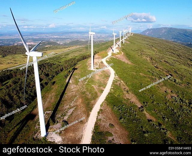 Aerial view of windmills farm for renewable energy production on beautiful blue sky. Wind power turbines generating clean renewable energy for sustainable...