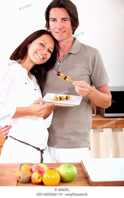 A couple eating fruit skewers