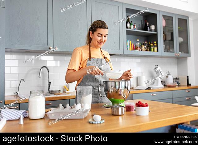 happy young woman cooking food on kitchen at home