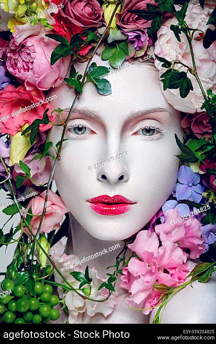 Beautiful young pale white woman with different flowers on head. Flower queen. Beauty shot