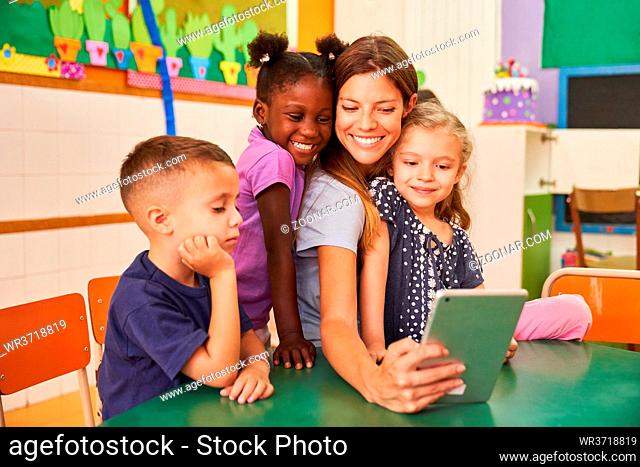 Kinder und Erzieherin machen ein Selfie mit Tablet Computer im internationalen Kindergarten