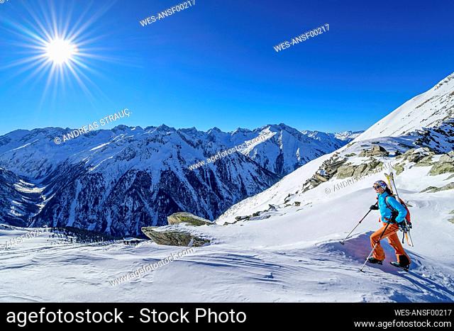Austria, Tyrol, Sun shining over female skier in Zillertal Alps