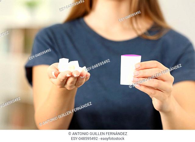 Front view close up of a woman hands holding sugar cubes and saccharin at home