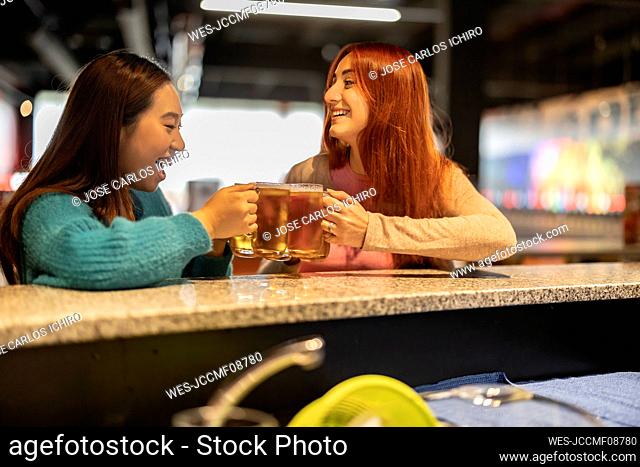 Young women holding glasses of beer at bowling alley