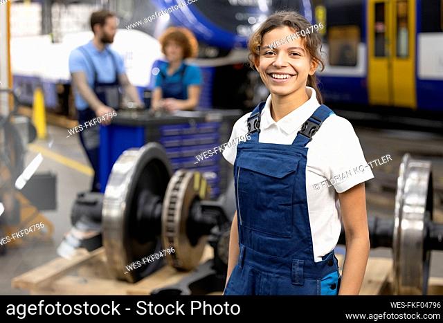 Happy young trainee standing in warehouse at industry