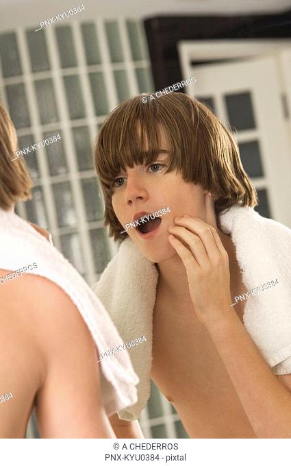 Boy examining his face in the bathroom mirror