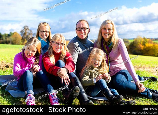 Family sitting on fall or autumn meadow