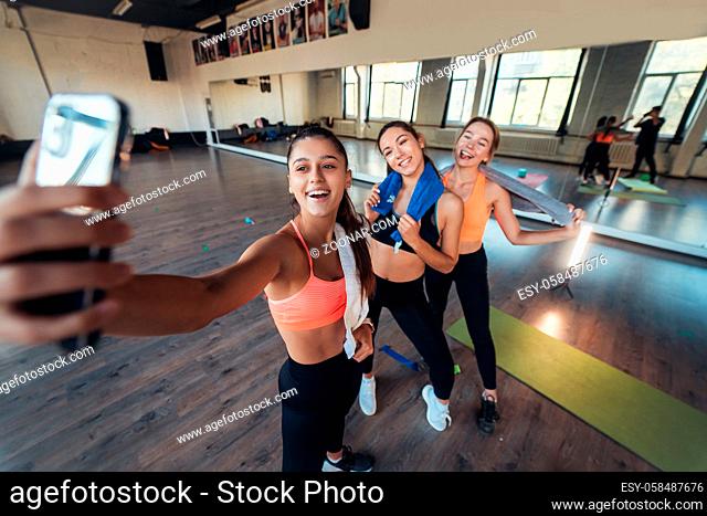 Two female friends taking a selfie photo after hard workout in gym