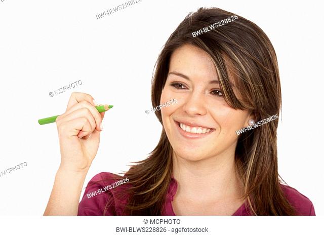 young woman drawing something on an imaginary glass pane in front of her with a bright green pencil