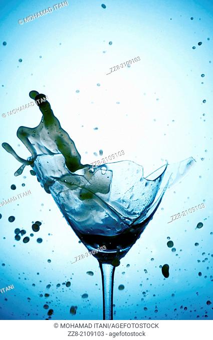 Powerful Splash breaking a martini glass , a conceptual image about alcohol addiction
