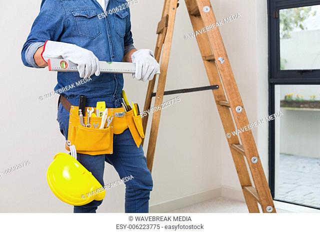 Mid section of a handyman with toolbelt and hard hat