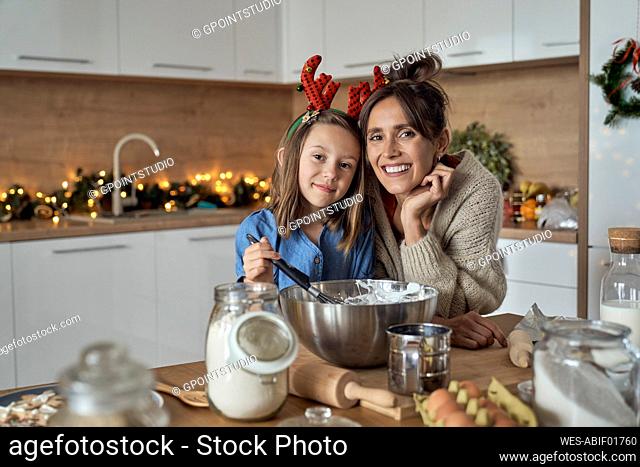 Smiling woman and daughter with mixing bowl in kitchen