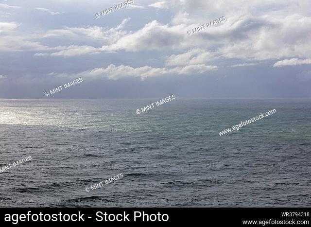 Storm clouds over the Pacific ocean at dusk, green and grey water surface, rain shower and rain cloud