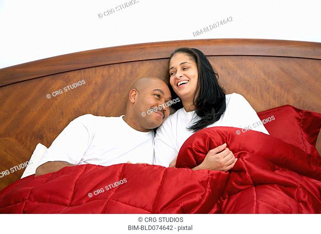 Dominican man lounging in bed with wife