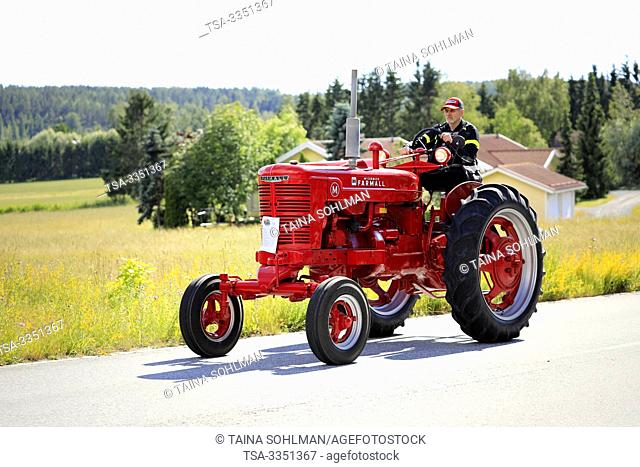 Kimito, Finland. July 6, 2019. Man drives red International Harvester Farmall M tractor, year 1951, on Kimito Traktorkavalkad, vintage tractor parade