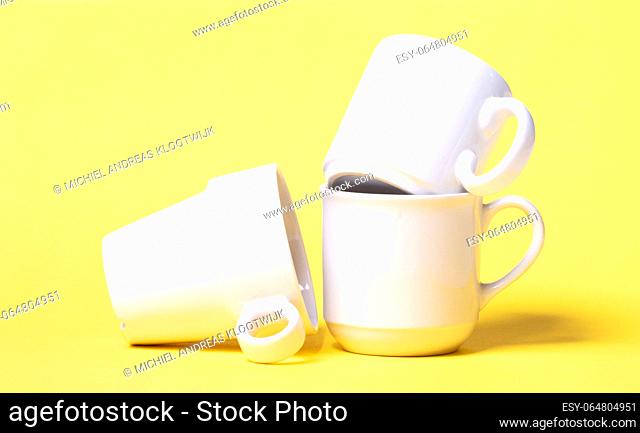 White coffee cups isolated on a solid yellow background