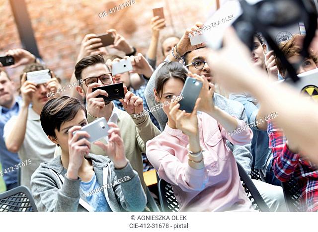 Audience using camera phones at technology conference