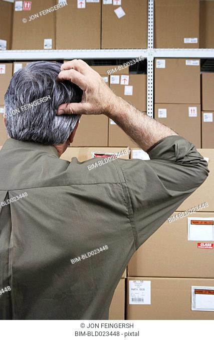 Businessman in warehouse scratching his head