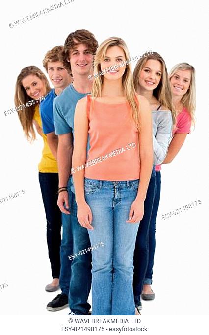 A full length shot of a smiling group standing behind one another at various ang