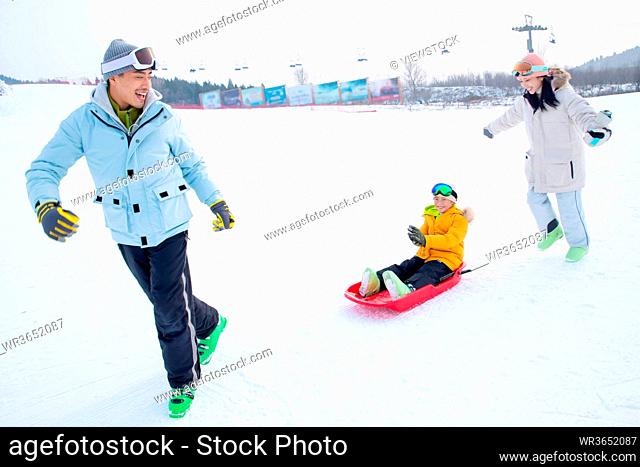 Parents and sitting in the snow ski son play skateboard