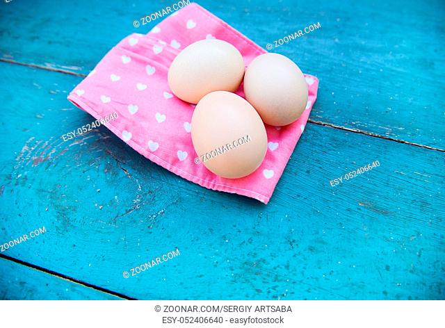 Eggs on pink tablecloth over grunge blue wooden background