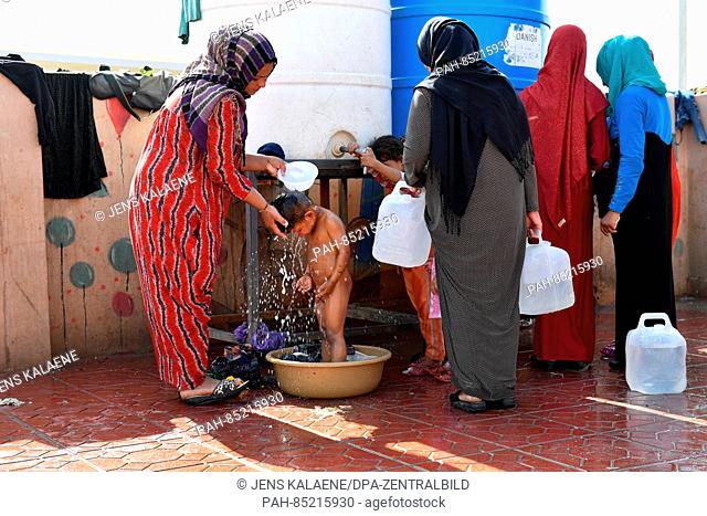 A refugee child being washed by its mother at the refugee camp Debaga between Erbil and Mossul, Iraq, 18 October 2016. More than 500