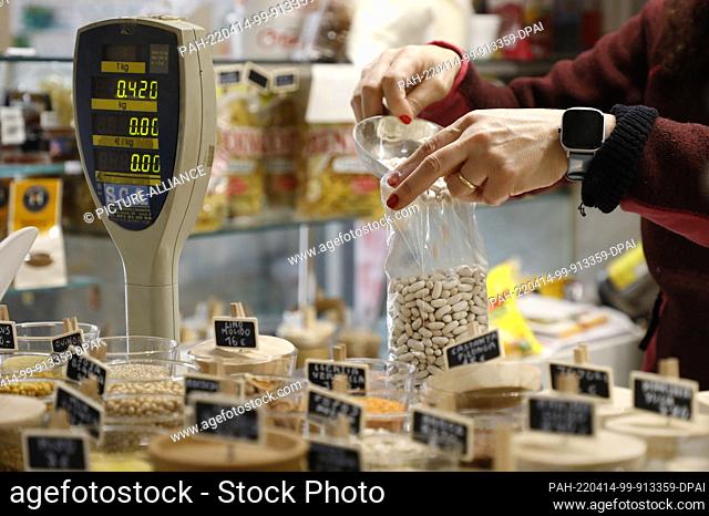 13 April 2022, Spain, Palma: A vendor prepares a bag of white beans for a customer at a stall in the Pere Garau market in Palma