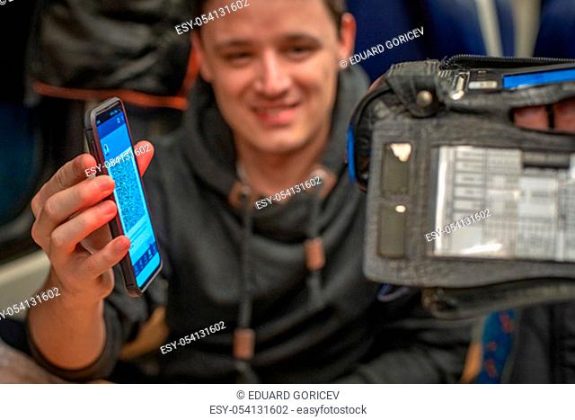 Young sympathetic man shows an electronic ticket conductor on the train on your smartphone. Checking by reading device