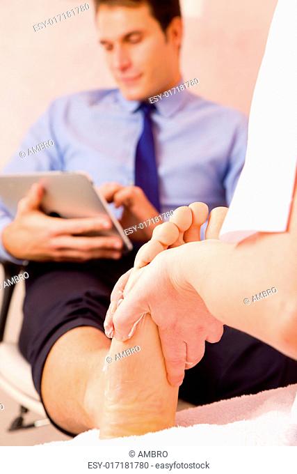 Therapist massaging businessman's foot