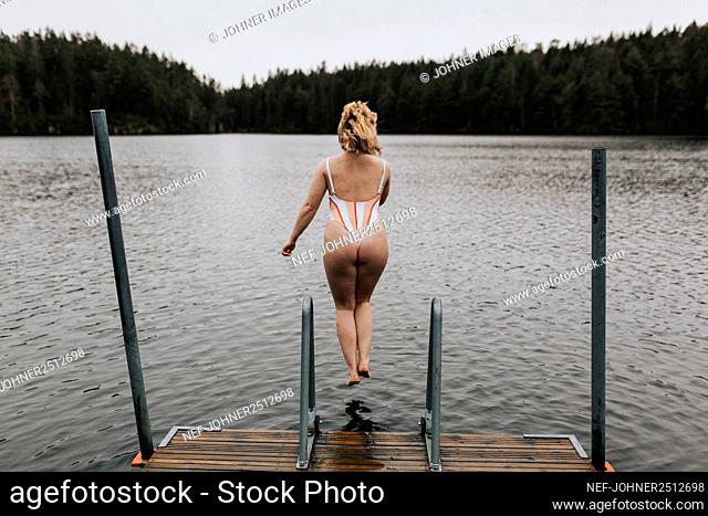 Rear view of woman jumping into lake