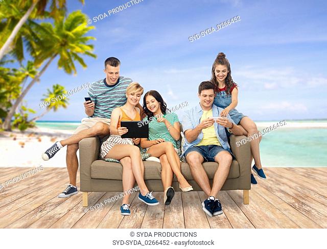 friends with tablet pc and smartphones over beach