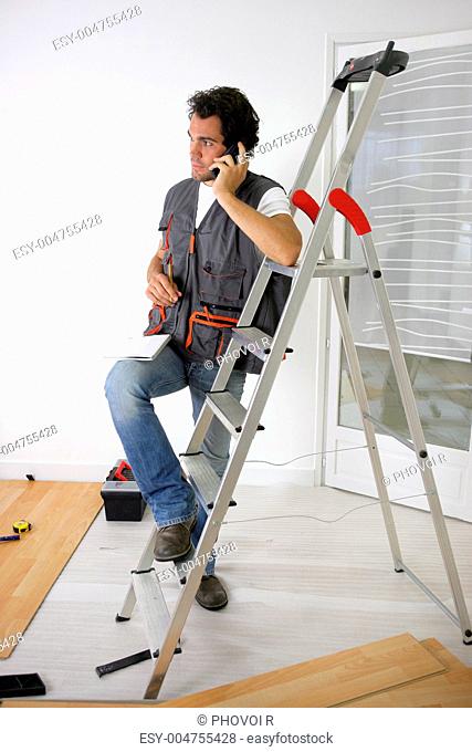 Man laying a floor and taking a phone call