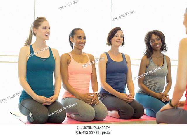 Smiling women listening to fitness instructor in exercise class gym studio